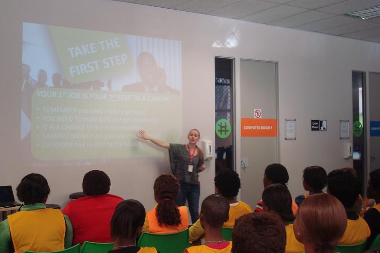 Teacher giving instructions in front of class of adults wearing yellow bibs