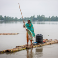 Woman steering a raft in deep flood water in Bangladesh