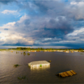 Landscape image of large flood with the roof of a house visible in the middle