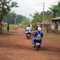 Photo of motorbike drivers and health workers delivering vaccines through a village in rural Sierra Leone