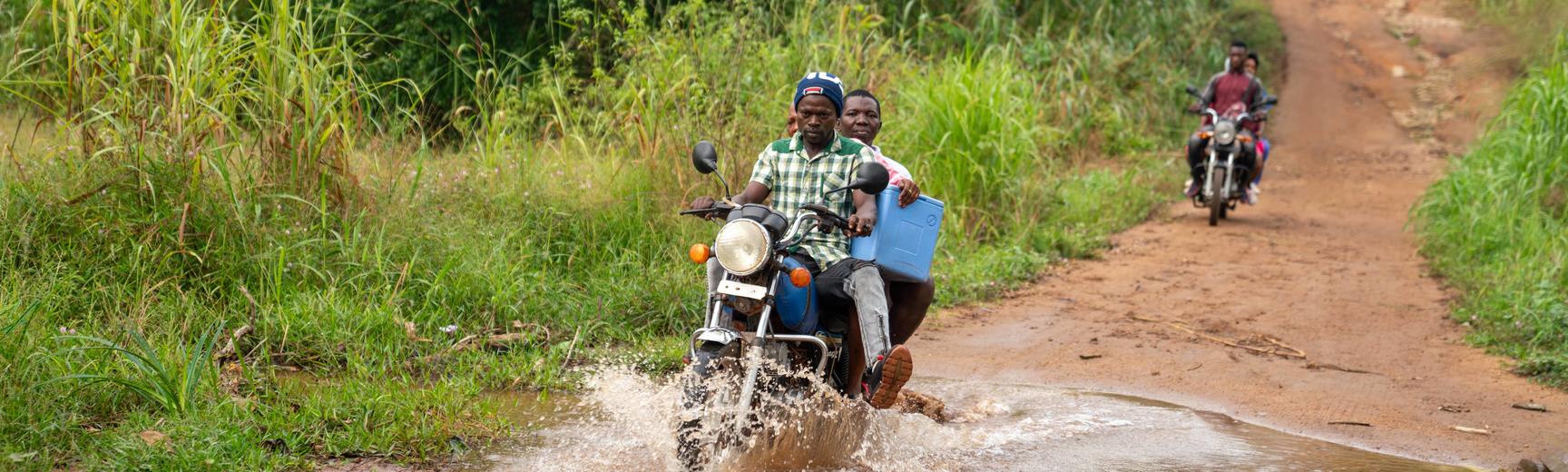 Motorbike driver and health worker delivering vaccines in rural sierra leone