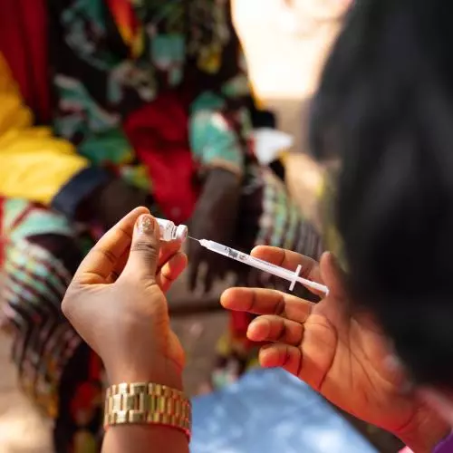 A person prepares a syringe with the COVID-19 vaccine, close up of hand and cooler box.