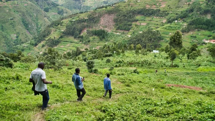 Men walk through the grass in the hills of Western Kenya