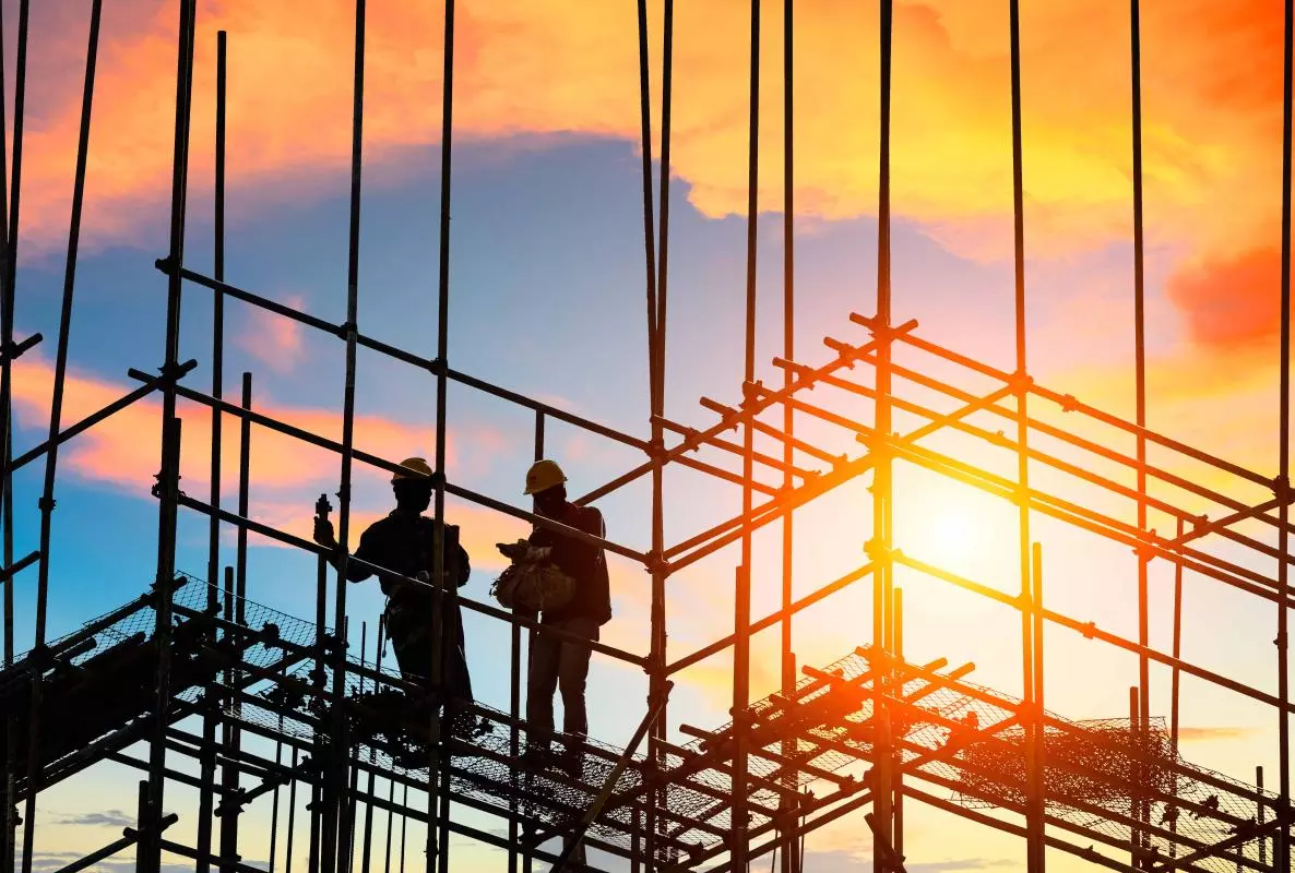 workers and construction site at sunset