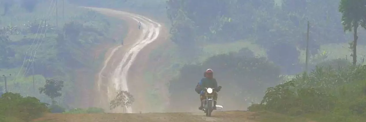 Person riding motorbike on dusty track through countryside in Western Kenya